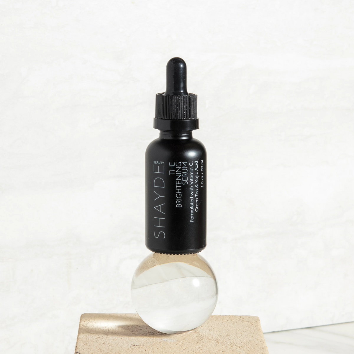 Image of THE VITAMIN C BRIGHTENING SERUM in a dropper bottle on a decorative surface.