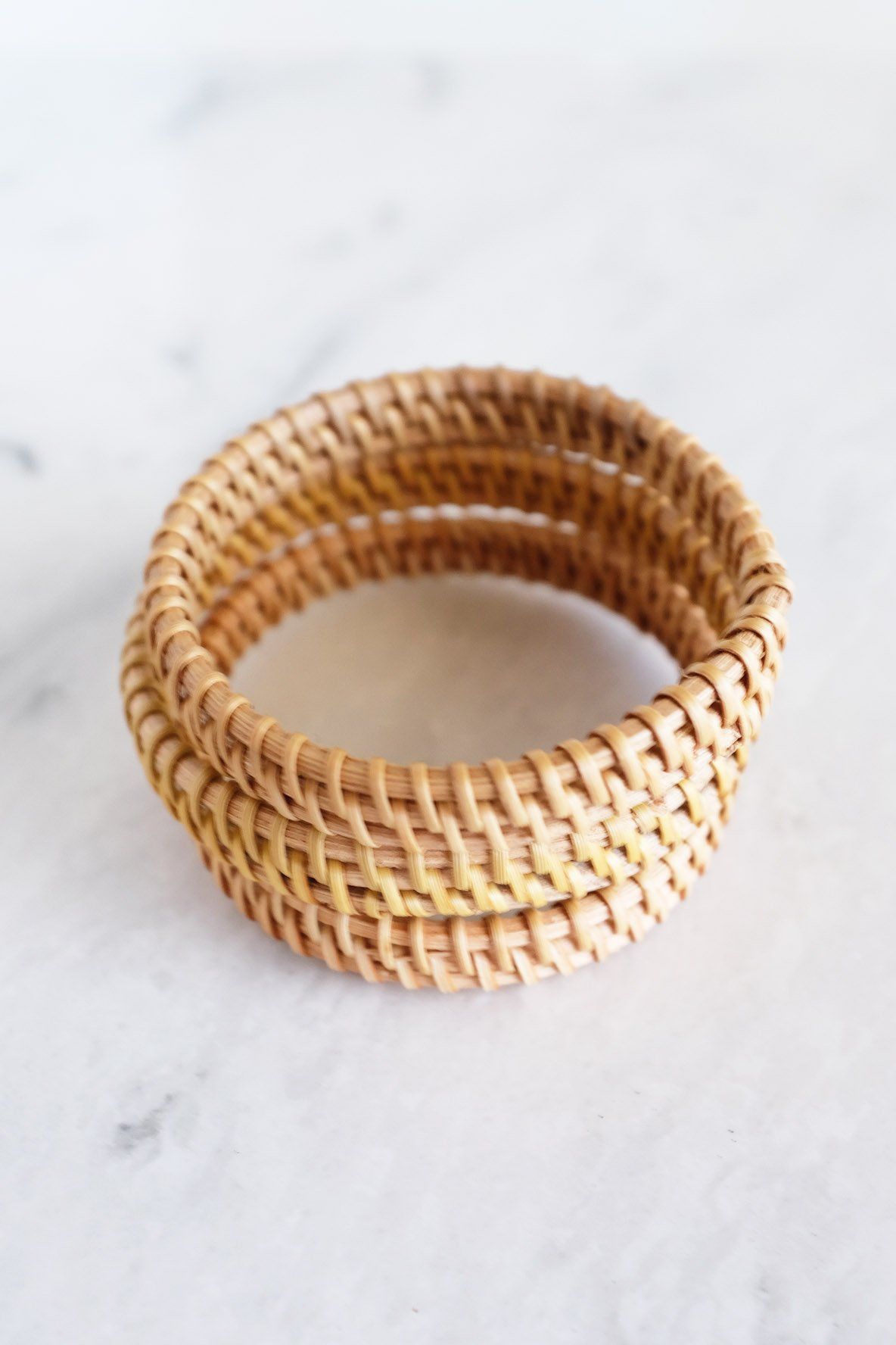 Natural Rattan Bangle Bracelets stacked in a 3-piece set on a marble surface.