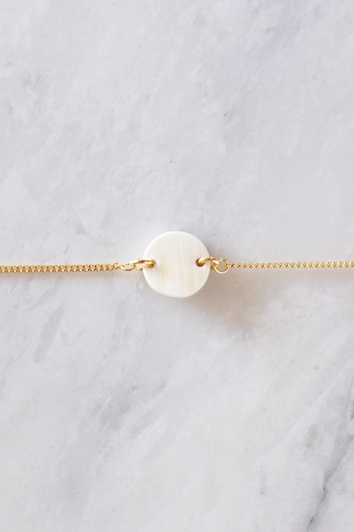 Tran Quoc Dainty Buffalo Horn Charm Bracelet featuring a circular buffalo horn charm on a delicate gold chain.