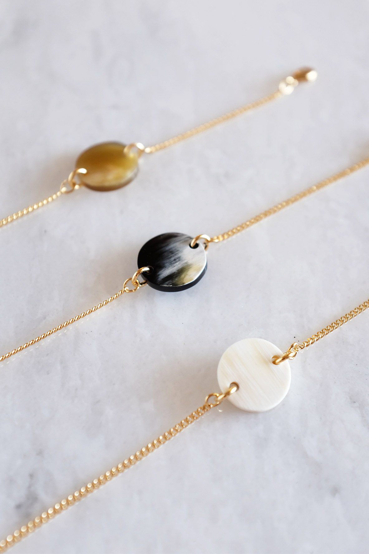 Tran Quoc Dainty Buffalo Horn Charm Bracelet featuring circular horn charms on a delicate gold chain.