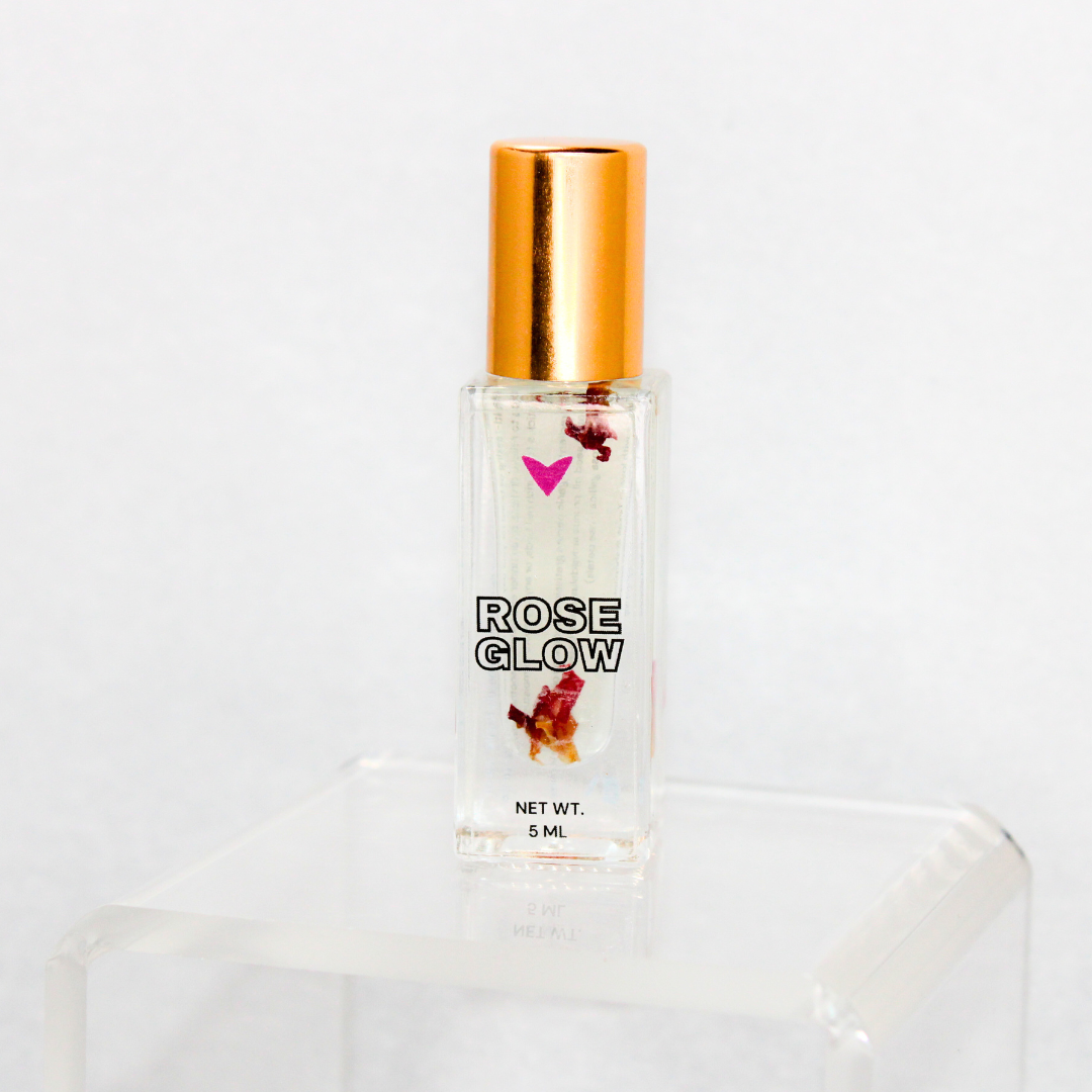 Rose Glow Lip Oil in a clear bottle with golden cap, showcasing rose petals for glossy shine lip care.