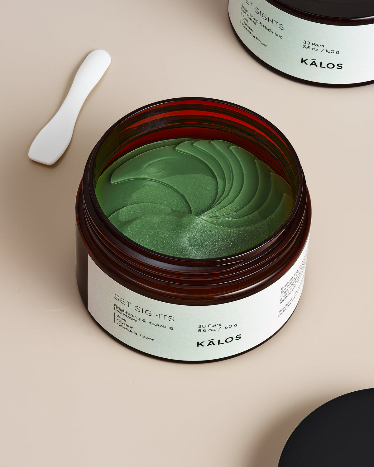 Brightening & Hydrating Eye Masks from Set Sights in a jar with a green mask texture and applicator spoon.