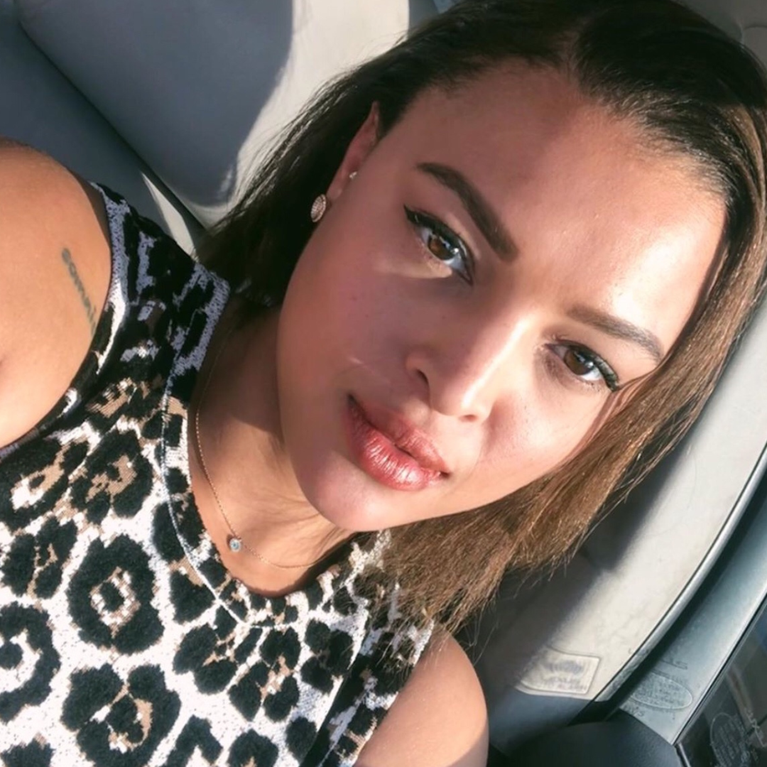 Close-up selfie of a woman with a natural makeup look, wearing a leopard print top.