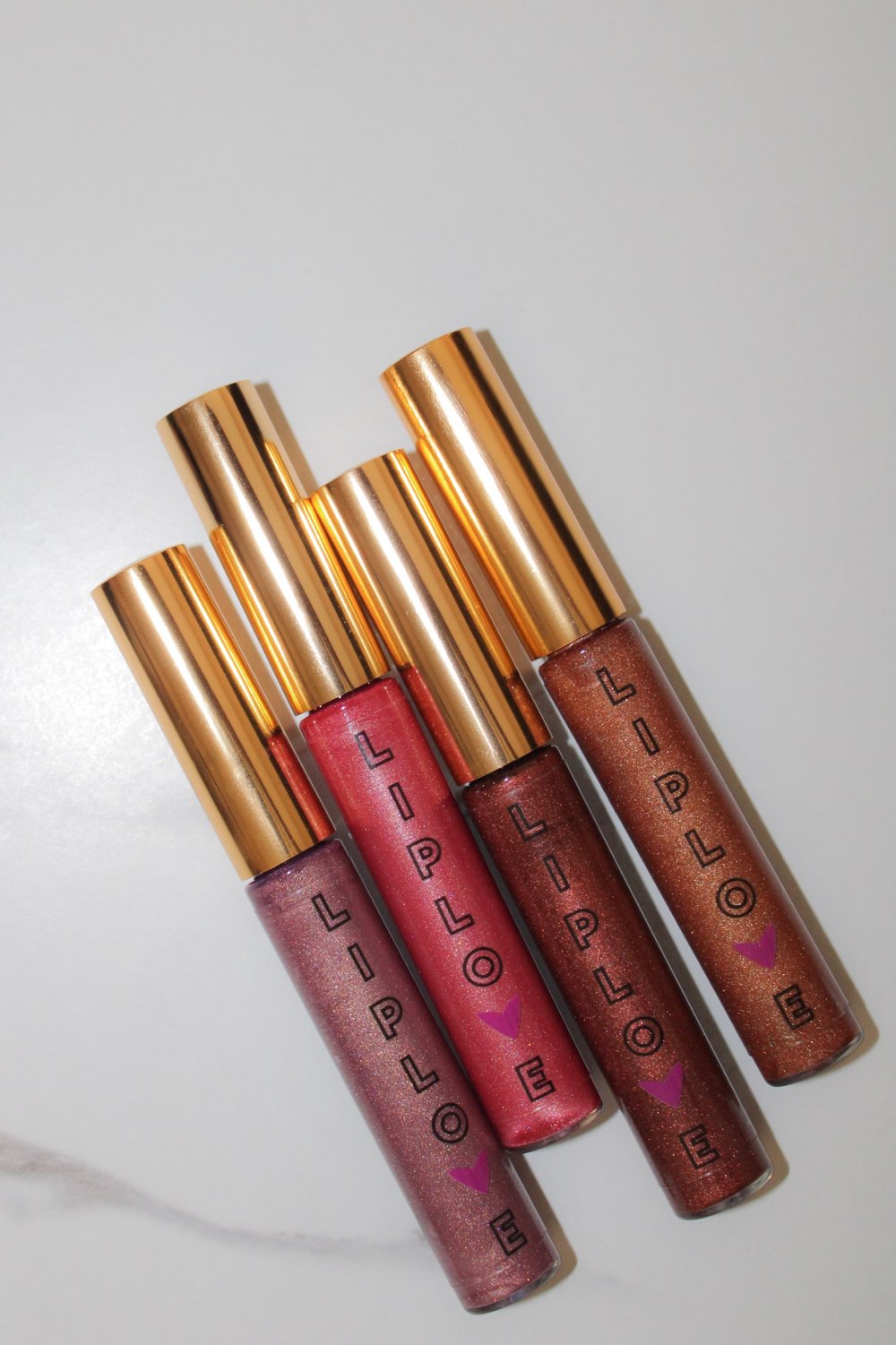 Pop of Color Beauty Kit featuring vibrant lip glosses in shades of pink and brown on a marble background